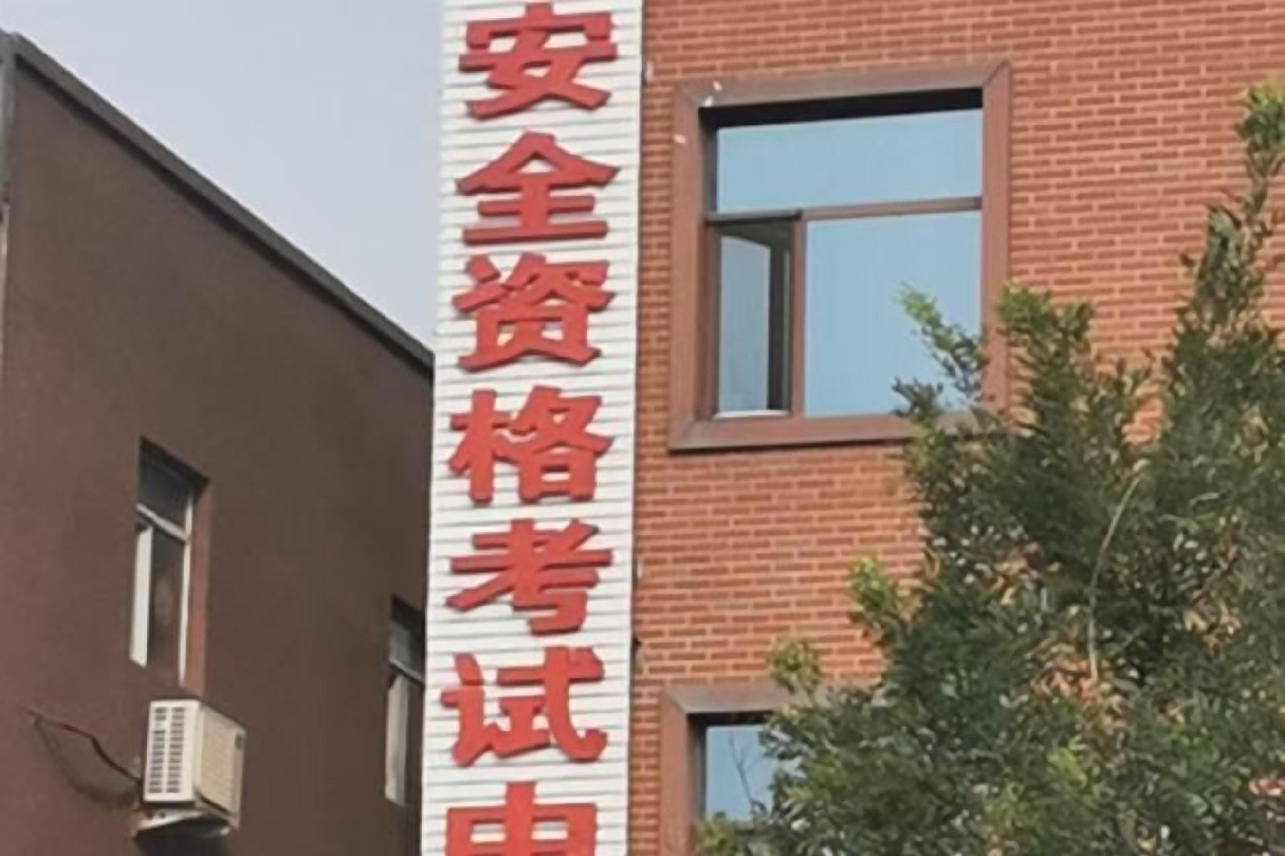 Un bâtiment sur lequel est apposée une enseigne indiquant « 安全资格考试 », ce qui se traduit par « Examen de qualification en matière de sécurité ».