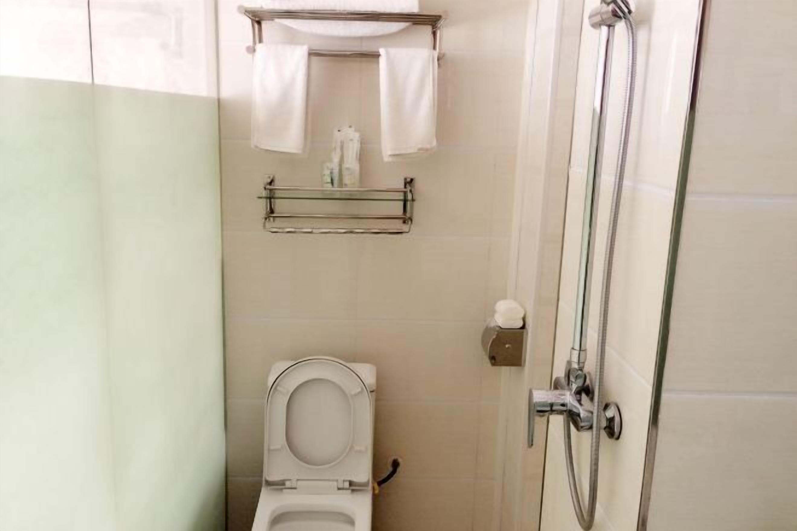 A small, clean bathroom with a toilet, a shower, and a towel rack.