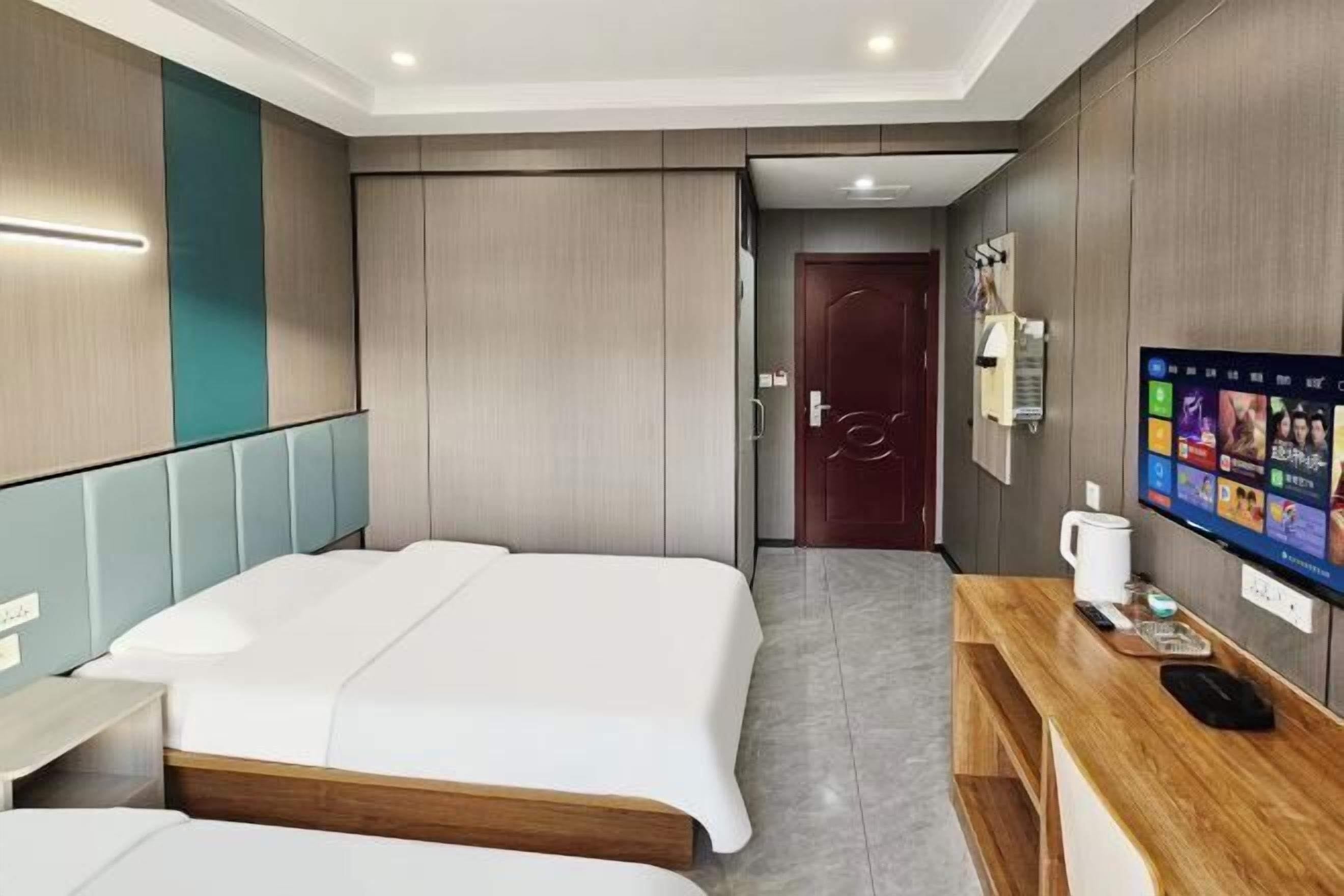 Habitación de hotel con dos camas, un escritorio de madera, una televisión y una puerta que da a un baño.