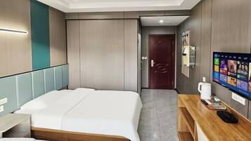 Habitación de hotel con dos camas, un escritorio de madera, una televisión y una puerta que da a un baño.