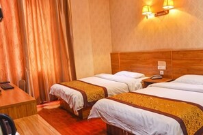 A hotel room with two beds, a wooden headboard, a desk, and a telephone.