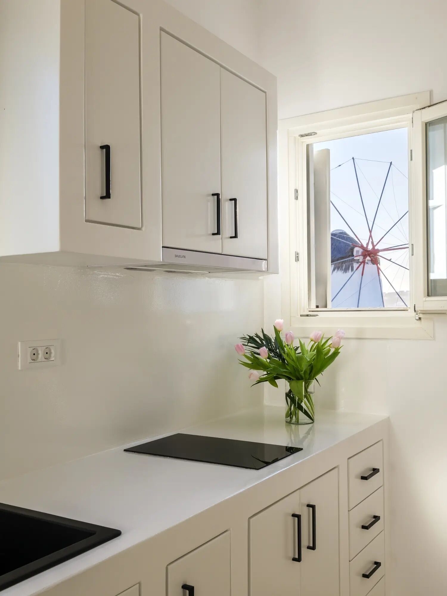 A kitchen with white cabinets, a black countertop, and a window with a view of a Ferris wheel.