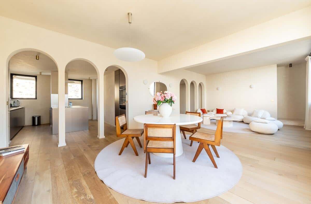 A modern interior with a round dining table, wooden chairs, and a white rug.