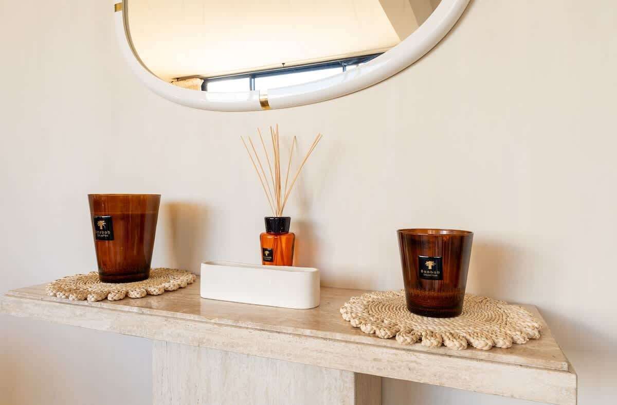 Un lavabo da bagno con due portacandele marroni e un diffusore.