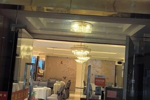 Un vestíbulo de hotel con una araña, un área de descanso y una recepción.