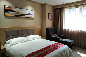 Una camera d'albergo con un letto, una sedia, un comodino, un quadro e una finestra con tende.