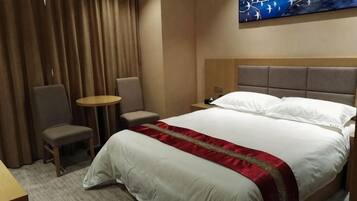 Een hotelkamer met een bed, twee stoelen, een klein tafeltje en een schilderij aan de muur.