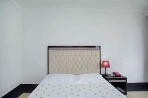 A hotel room with a bed, a nightstand, and a lamp. - Yun Hai Hotel (Shanghai)