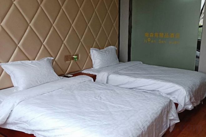Habitación de hotel con dos camas, un cabecero acolchado y una pared con texto.