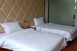 Een hotelkamer met twee bedden, een gestoffeerd hoofdeinde en een muur met tekst.