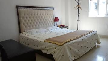 A neatly made bed with a headboard, a bedside table with a lamp, and a floor lamp.