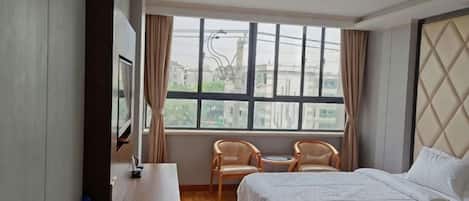 Una camera d'albergo con un letto, una scrivania, una sedia e una finestra.