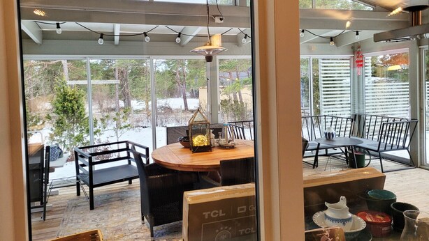 A dining area with a round table, chairs, and a view of a snowy landscape through large windows.