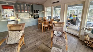 A spacious kitchen with modern appliances, a dining area with wooden chairs, and large windows offering views of the outdoors.