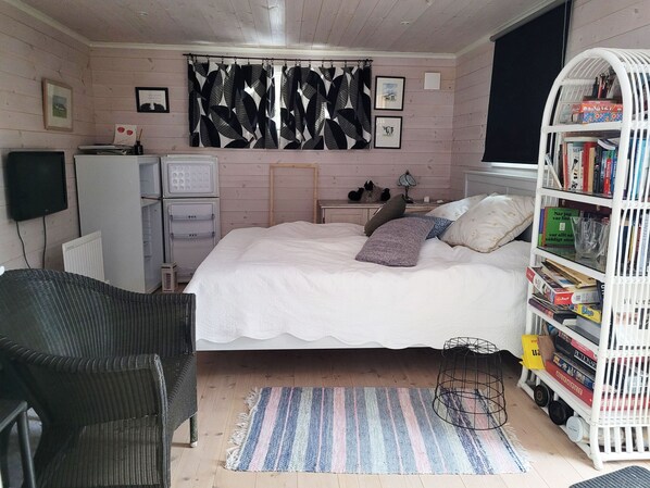 Un dormitorio con una cama, una silla, una estantería y un radiador.