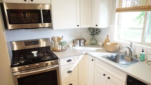 A modern kitchen with stainless steel appliances, white cabinetry, and a window providing natural light.