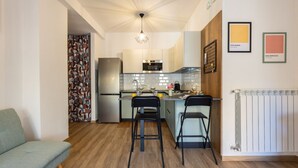 A compact kitchen with modern appliances, two bar stools, and a dining area. - Domus Aqua Alexandrina by Rentbeat (Roma)