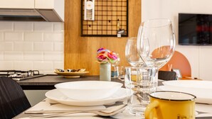 A dining table set with plates, cutlery, and a yellow mug, with a kitchen in the background. - Domus Aqua Alexandrina by Rentbeat (Roma)