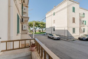 Eine Wohnstraße mit einem weißen Gebäude, einem Balkon mit einem Blumentopf und geparkten Autos.
