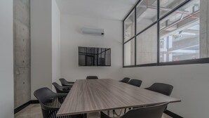 A conference room with a long table, six chairs, a large window, and an air conditioning unit on the wall. - RM 210 | Beauty, Balcony, Elevator, Security, Pool (Cali)