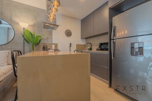 Una cocina moderna con una isla central, un refrigerador y un reloj en la pared.