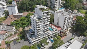 A multi-story residential building with balconies, a rooftop pool, and surrounding greenery. - RM 210 | Beauty, Balcony, Elevator, Security, Pool (Cali)