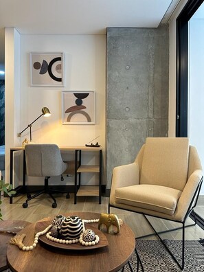 Una sala de estar moderna con un escritorio, un sillón cómodo y una mesa de centro con objetos decorativos.