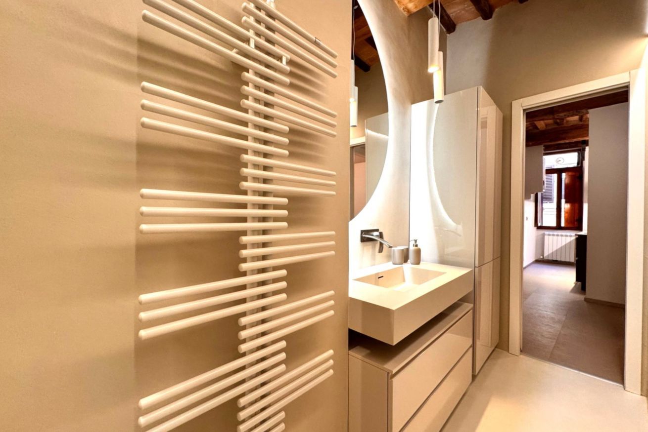 Ein modernes Badezimmer im minimalistischen Stil, mit einem weißen Waschbecken und einem einzigartigen Handtuchhalter an der Wand.