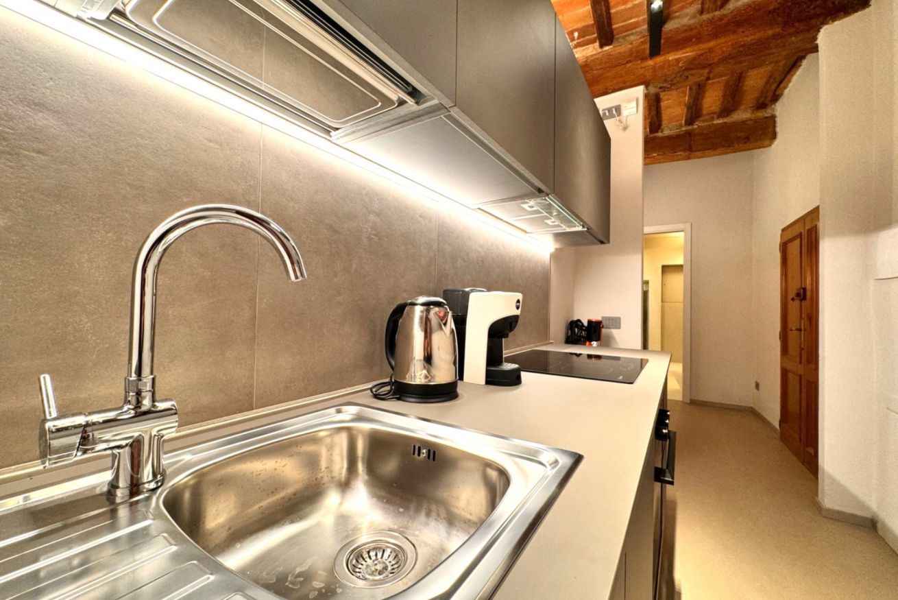 A modern kitchen with stainless steel appliances, a built-in sink, and a wooden ceiling.