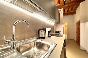 Una cucina moderna con elettrodomestici in acciaio inossidabile, lavello incassato e soffitto in legno.