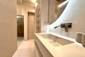 A modern bathroom with a white sink, a towel rack, and a mirror.