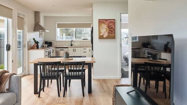 A modern kitchen with a central island, a dining area with a table and chairs, and a living room with a sofa and a TV. - Welcome to Birch BnB (Newstead)