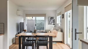 A modern living space with a dining area, a sofa, and a large window. - Welcome to Birch BnB (Newstead)