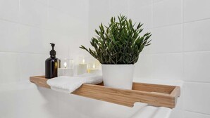 A bathroom with a wooden shelf holding a white towel, a black bottle, and a potted plant. - book2stay: Retro-Alpin Studio (Laax)