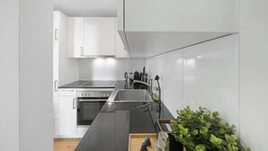Una cucina moderna con mobili bianchi, un piano di lavoro nero ed elettrodomestici in acciaio inossidabile.