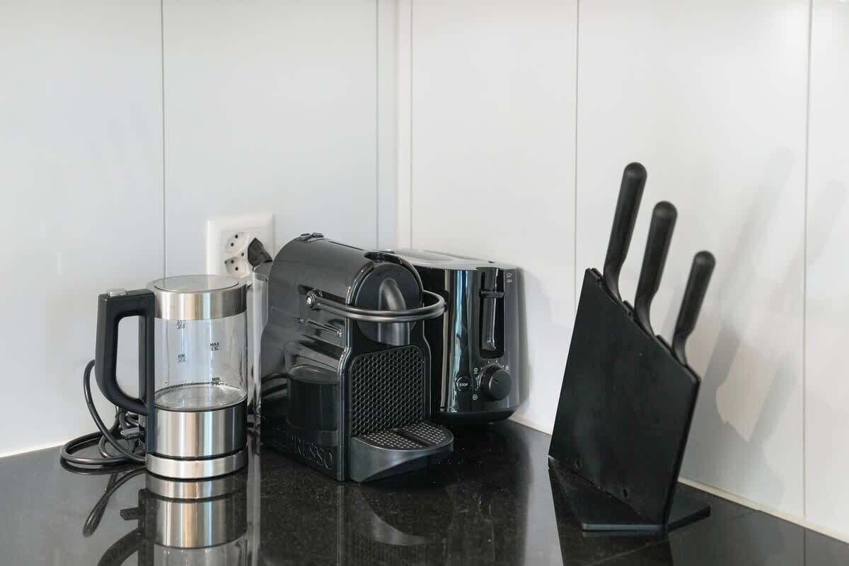 A kitchen with a coffee maker, toaster, and knife block on a black countertop.