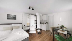 Una camera d'albergo moderna con un letto, un'area ristorazione e angolo cottura.