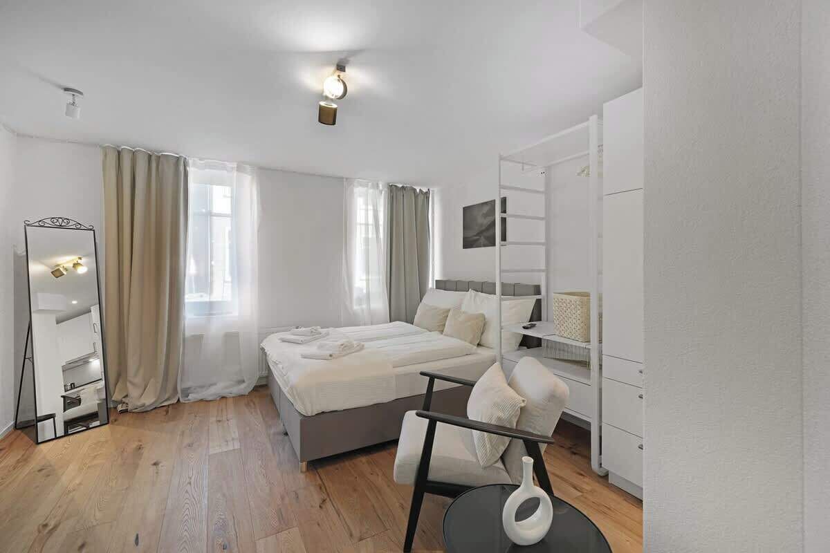 Een moderne slaapkamer met een bed, een stoel, een spiegel en een kledingkast.