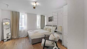 Een moderne slaapkamer met een bed, een stoel, een spiegel en een kledingkast.