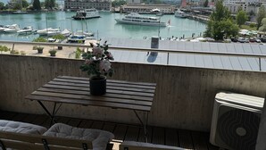 A balcony with a view of a marina, a potted plant, and a table. - book2stay: Lakefront Apt w/Balcony, near Harbor & Station (Romanshorn)