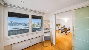 A modern room with a large window, a bed, a dining area, and a mirror. - book2stay: Lakefront Apt w/Balcony, near Harbor & Station (Romanshorn)