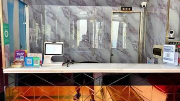A reception desk with a computer, a security camera, and a QR code on the counter.