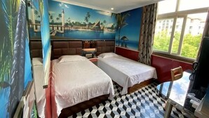 Habitación de hotel con dos camas, piso de cuadros, un mural con escena de playa y ventana que da a zonas verdes.