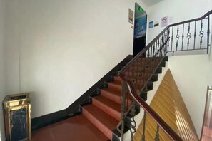 A staircase with a handrail and a wall-mounted sign. - Jujia Hostel (Shanghai)