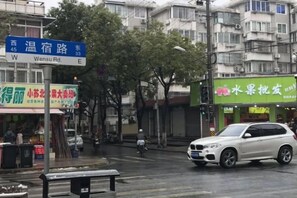 A street view with a sign for Wensu Rd, a fruit shop, and a white SUV. - Jujia Hostel (Shanghai)