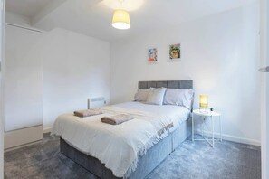 Une chambre à coucher avec un lit, une table de chevet et des œuvres d’art murales.