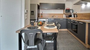 Una cocina moderna con comedor, que cuenta con una isla central, muebles oscuros y un microondas.