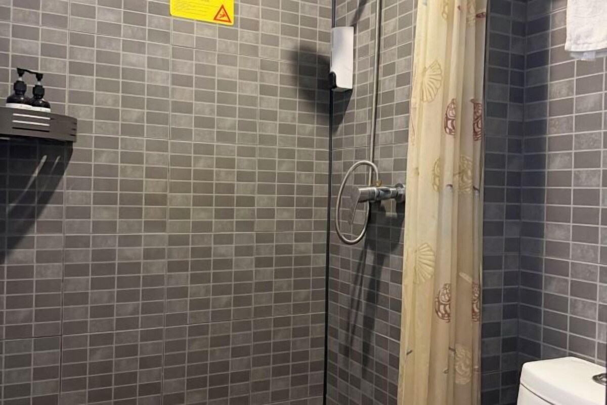A bathroom with a tiled wall, a shower with a glass door, and a toilet.
