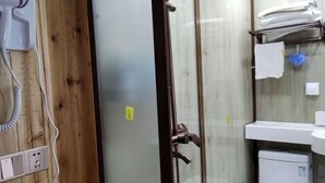 A bathroom with a glass shower enclosure, a white toilet, and a sink with a towel hanging on a rack. - Chiyou Valley Homestay (Xinhua)
