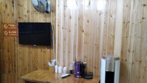 A wooden wall with a mounted television, a small table with various items, and a trash can. - Chiyou Valley Homestay (Xinhua)